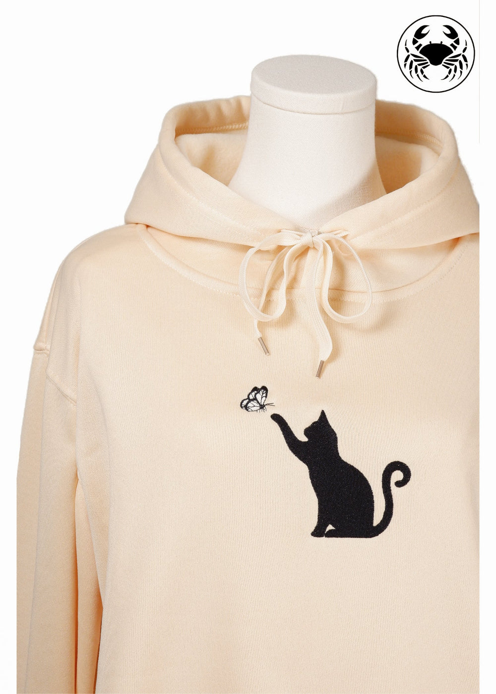 Unisex light beige hoodie with a front kangaroo pocket, drawstring hood, and an embroidered chest design featuring a black Cat Caught in a Moment with Butterfly