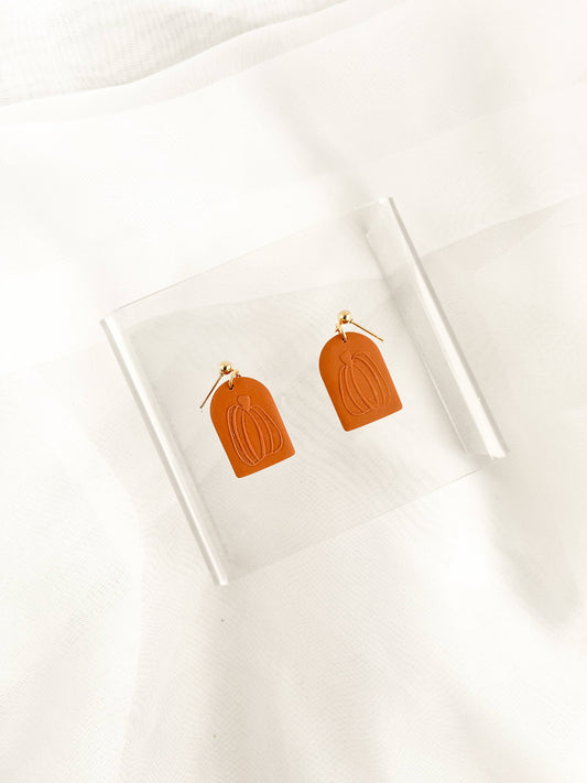 Pair of Zoey Pumpkin Dangle Earrings, featuring handmade rectangular rust-orange polymer clay charms with embossed pumpkin outlines and gold hooks